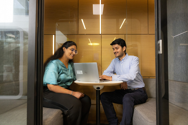An image of two workers in a meeting pod.